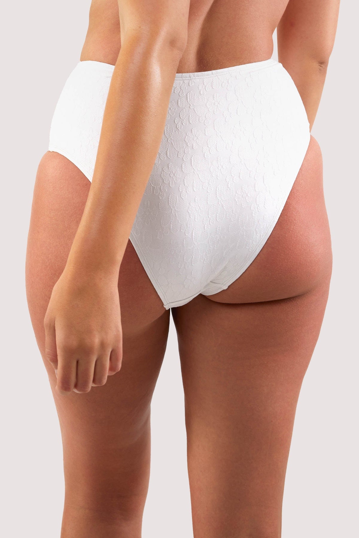 Model shows full brief of white floral texture high waist bikini bottoms