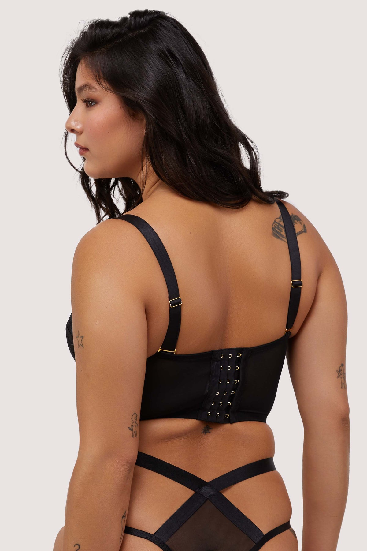 Model shows hook and eye fastening back and adjustable shoulder straps of black mesh bustier